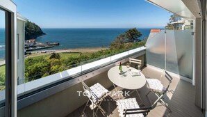 A balcony with a round table and chairs, overlooking a coastal view with a clear sky. - Panoramic Sea Views, Private Balcony & Sauna (Lynmouth)