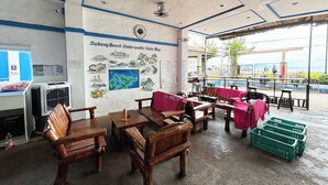 Un ristorante sulla spiaggia con mobili in legno, una mappa illustrativa al muro e vista sul mare.