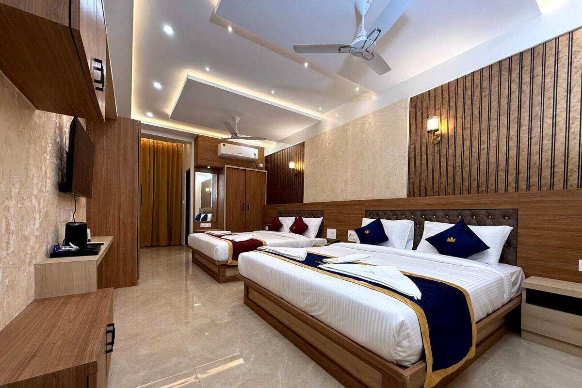 A modern hotel room with a large bed, a desk, and a ceiling fan.
