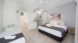 Un dormitorio con una cama grande, una mesita de noche, un armario y un ventilador de techo.