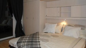 A bedroom with a bed, a bedside table, a lamp, and a wardrobe. - Apartment 'Studio in Sankt Blasien' with Balcony and Wi-Fi (St Blasien)