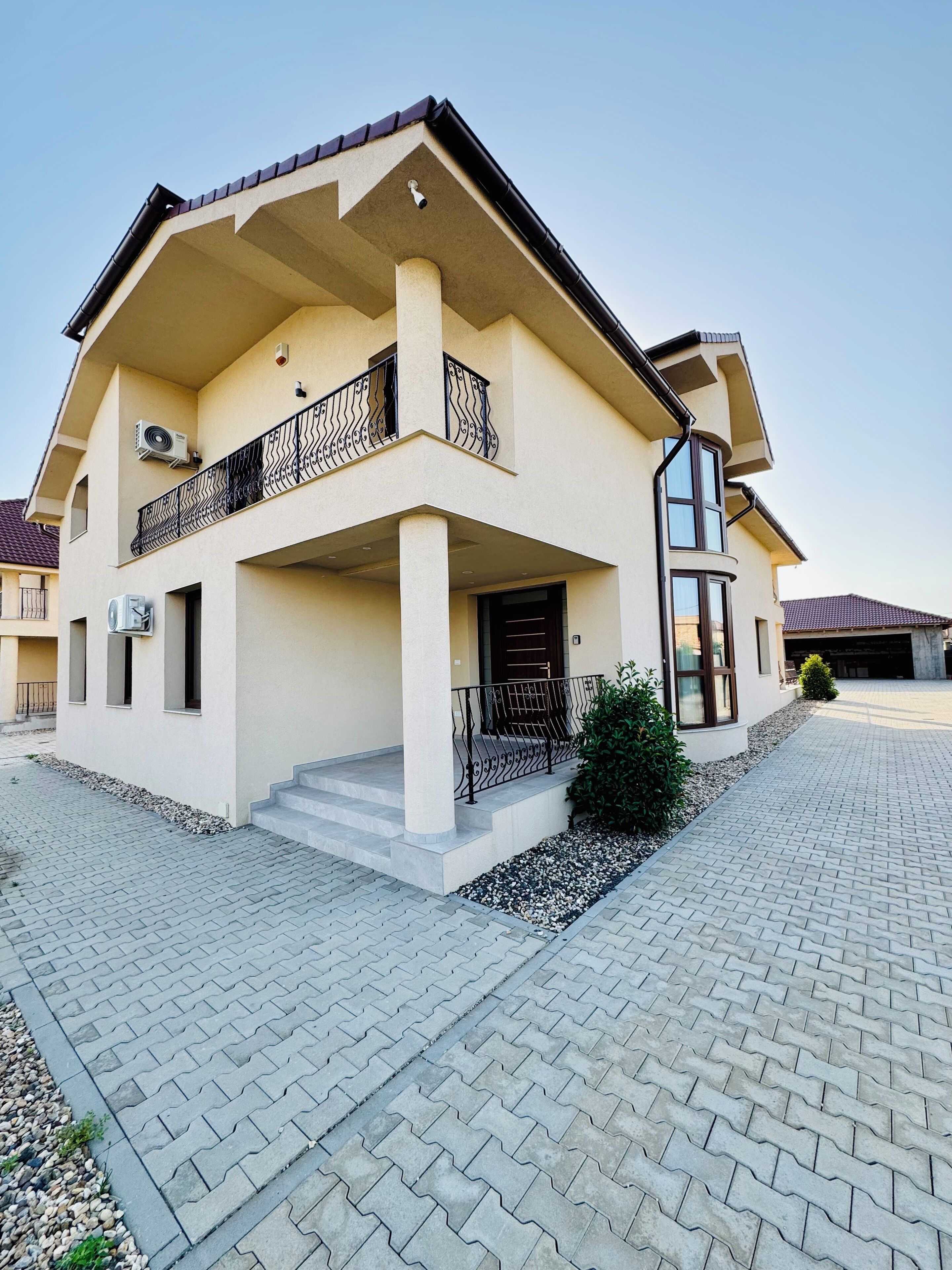 Une maison à deux étages avec un balcon, une allée et un petit jardin.