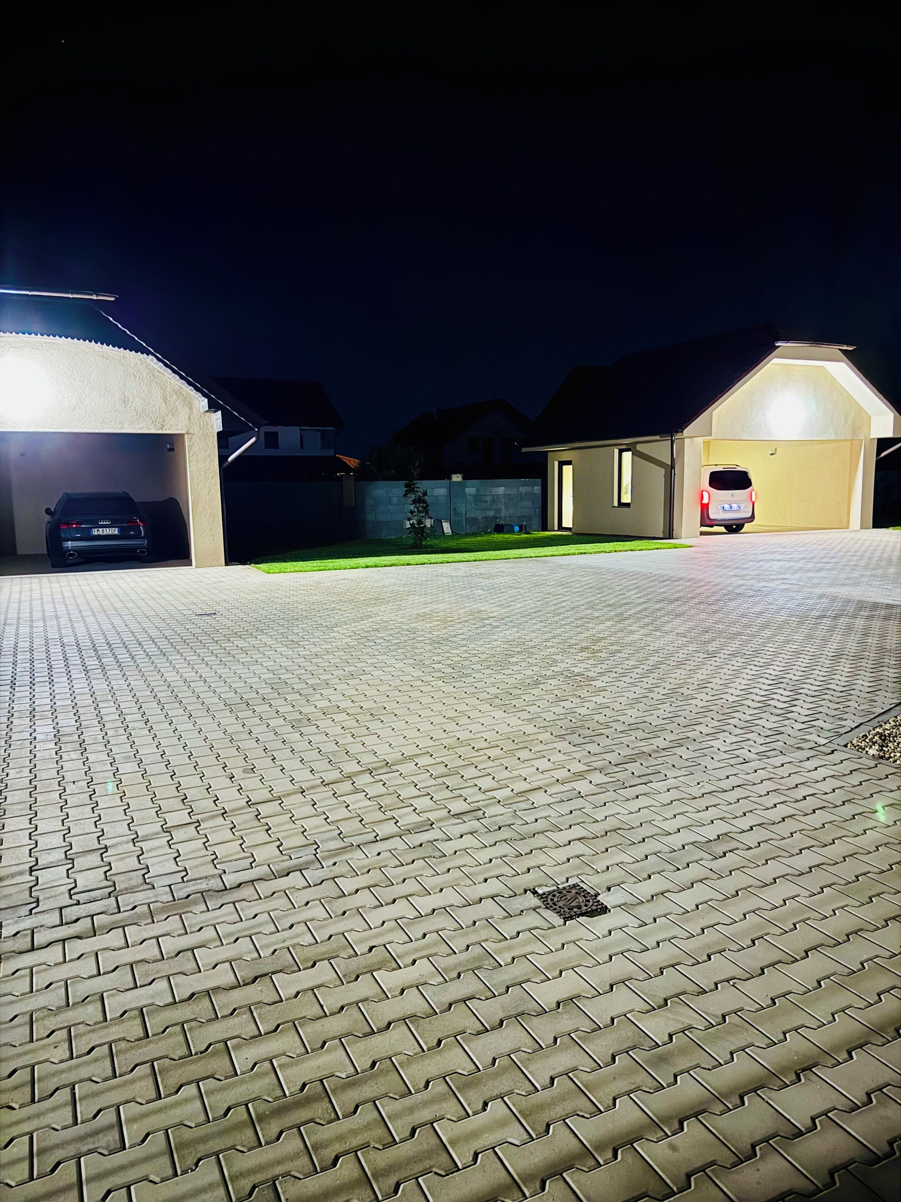 A paved driveway leading to a garage with two cars parked inside.