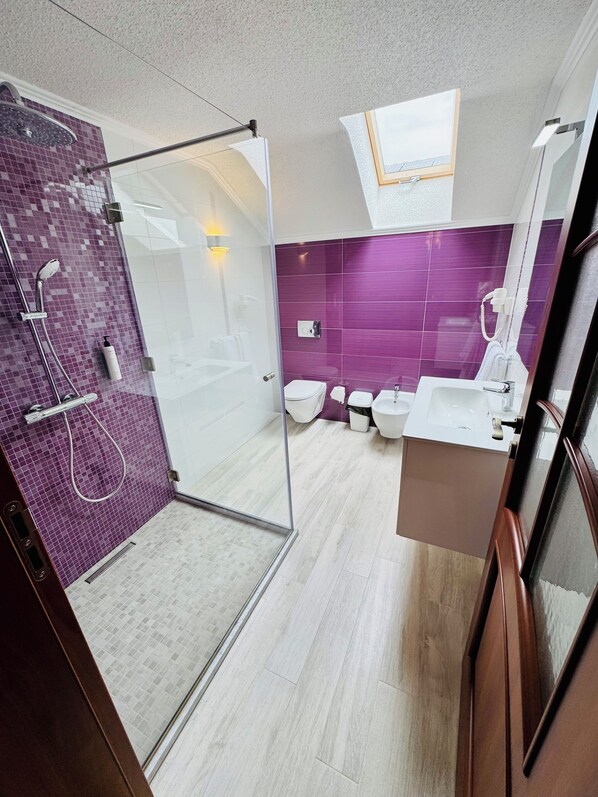 A modern bathroom with a glass-enclosed shower, a skylight, and a vanity with a mirror. - Roua Residence (Vladimirescu)