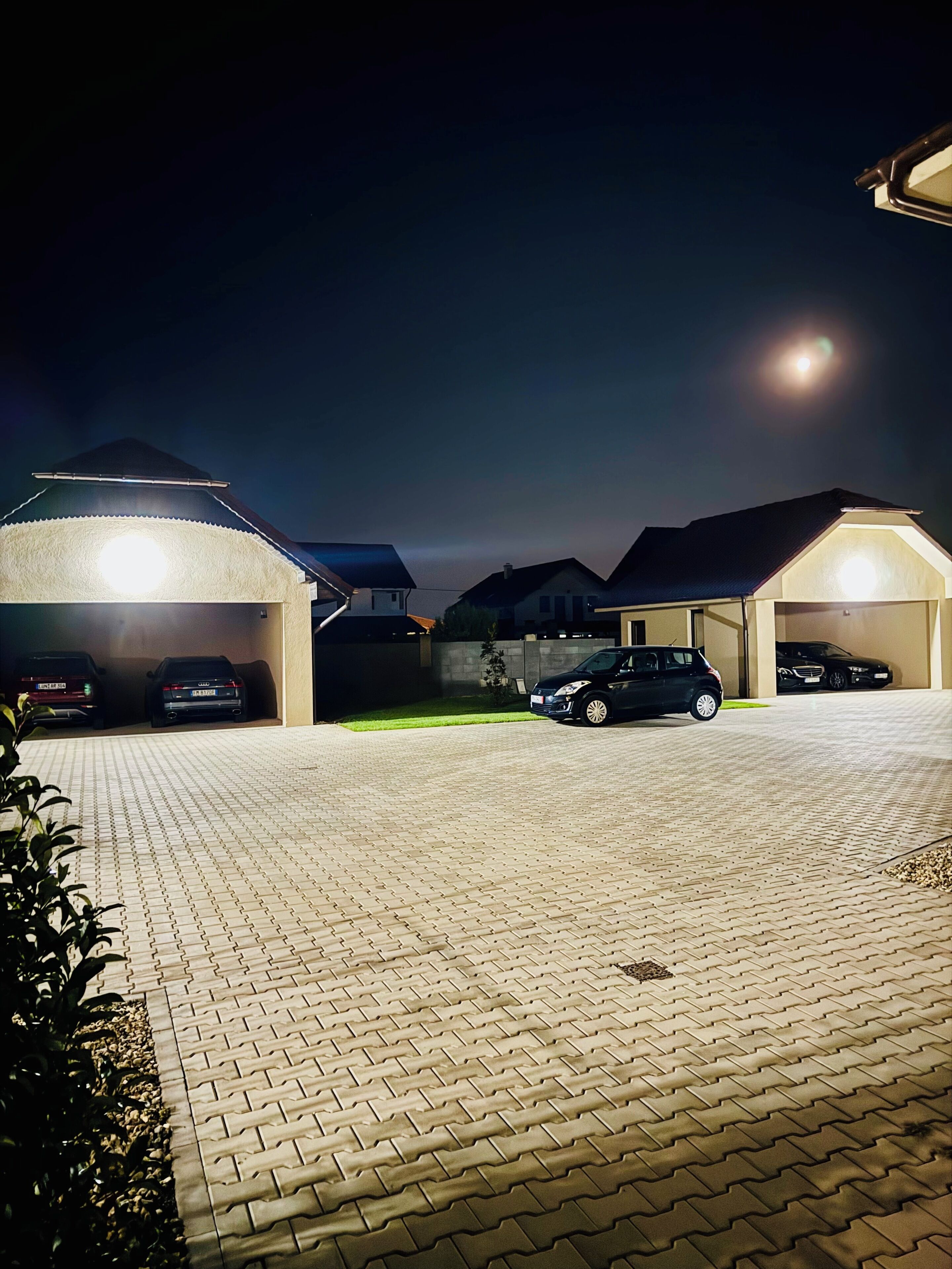 A parking area with multiple cars and a building with a lit roof.