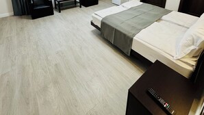 Ein Hotelzimmer mit Bett, Schreibtisch, Sessel, Fernseher, Kühlschrank und einer Tür.