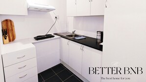 Una cocina moderna con armarios blancos, encimera negra y estufa integrada.