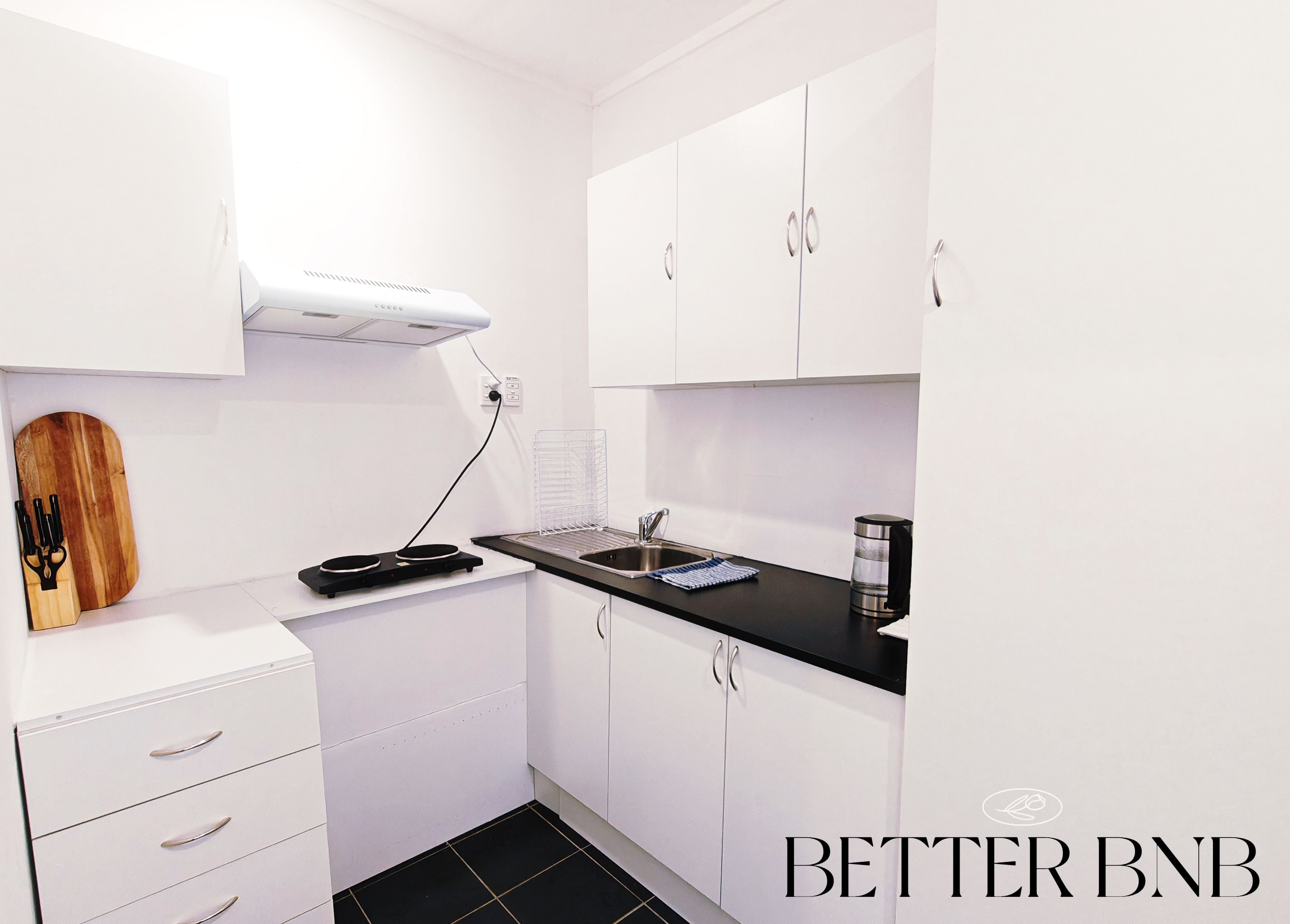 A modern kitchen with white cabinets, a black countertop, and a built-in stove.