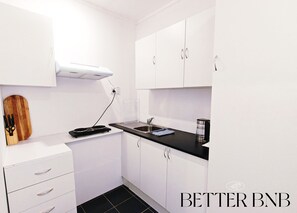 A modern kitchen with white cabinets, a black countertop, and a built-in stove. - Affordable Value Semi-Detached Home · 2BR · 3 Beds (Lower Hutt)