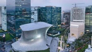 Un paysage urbain moderne, avec divers immeubles de grande hauteur, dont une structure métallique remarquable et un bâtiment en construction.