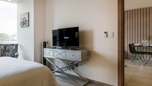Une chambre d’hôtel avec un lit, un téléviseur posé sur un meuble, un coin repas avec une table et des chaises, et une vue sur la ville.
