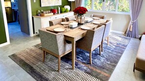 Un coin repas avec une table en bois dressée pour quatre personnes, entourée de chaises à motifs.