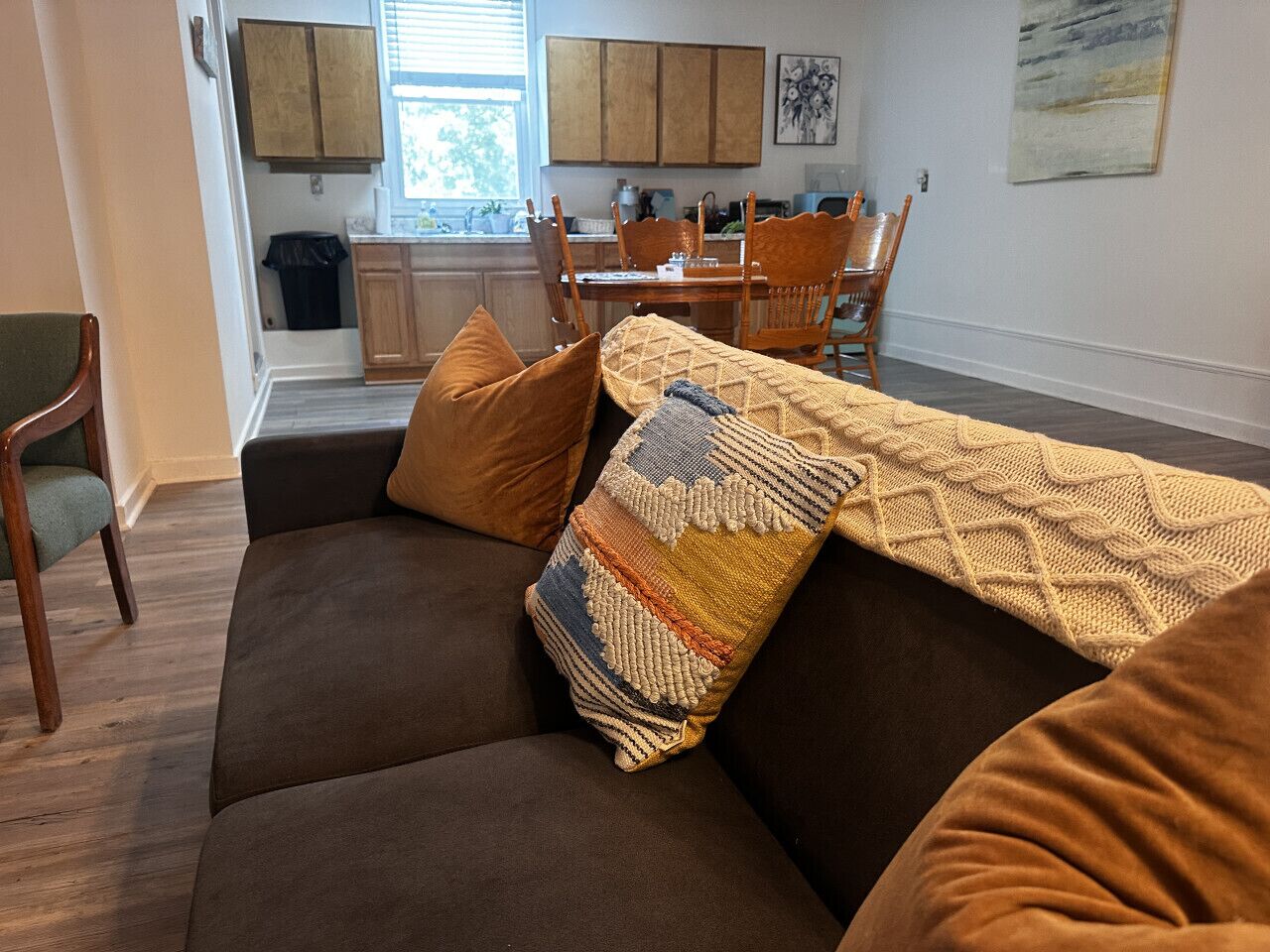 Una sala de estar con un sofá marrón, almohadones estampados y una mesa de centro de madera.