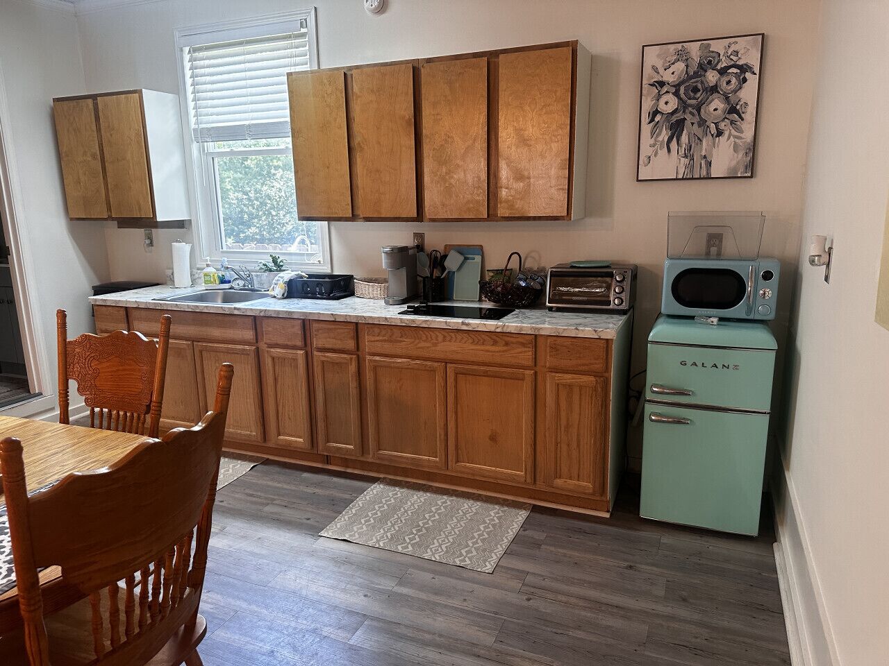 A kitchen with wooden cabinets, a vintage Galanz refrigerator, and a dining area with a table and chairs.
