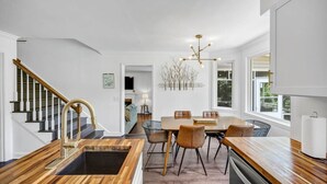 Eine moderne Küche mit einer Holz Arbeitsplatte, einer integrierten Spüle und einem Essbereich mit Tisch und Stühlen.