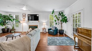 Ein Wohnzimmer mit Kamin, einer Couch, einem Couchtisch, einem Fernseher und einem Klavier.