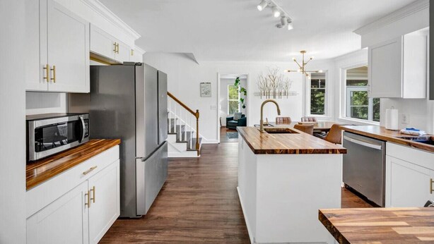 Eine moderne Küche mit weißen Schränken, Edelstahlgeräten und einer Holztischinsel.