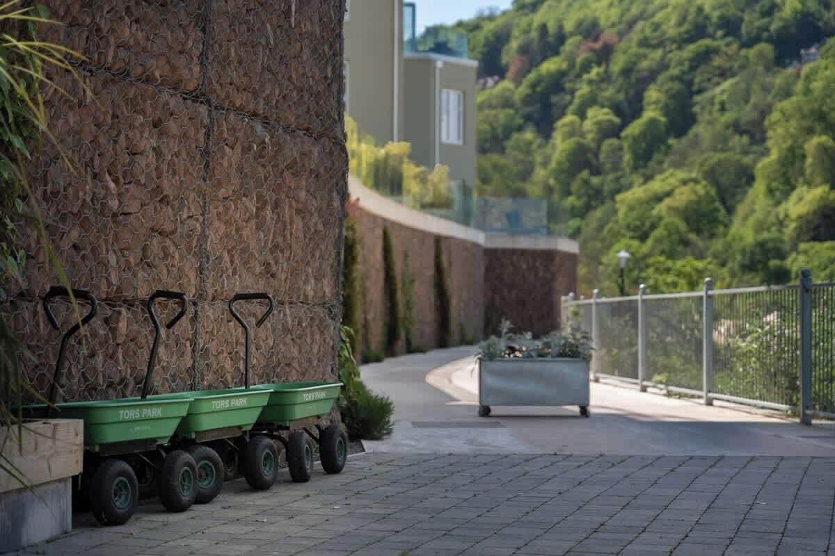 A paved pathway with green wheelbarrows labeled "TORS PARK" and a planter box.