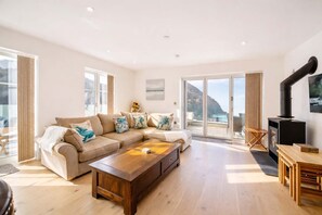 A spacious living room with a large sofa, a wooden coffee table, and a fireplace.