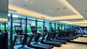 A gym with treadmills, exercise bikes, and a TV screen. - LUX  The Address Opera Downtown Suite (Dubai)
