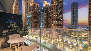 A modern hotel room with a balcony overlooking a cityscape at dusk. - LUX  The Address Opera Downtown Suite (Dubai)