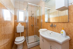 A bathroom with a toilet, shower, and sink.