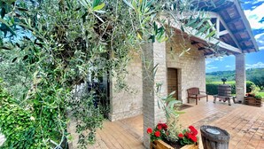 A rustic stone building with a wooden porch, a brick pathway, and a wooden barrel. - Spoleto Tranquilita sleeps 16 with Wifi Pool Yoga Studio Gardens and Views (Scuola di San Nicolò)