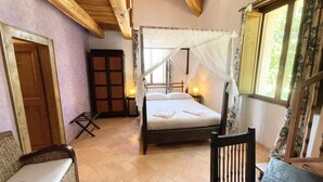 A bedroom with a four-poster bed, wooden ceiling beams, a window with floral curtains, and a nightstand with a lamp. - Spoleto Tranquilita sleeps 16 with Wifi Pool Yoga Studio Gardens and Views (Scuola di San Nicolò)