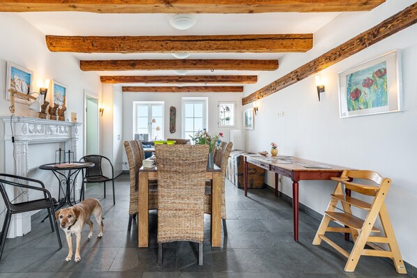Un coin repas avec une table en bois, des chaises en osier et un chien.