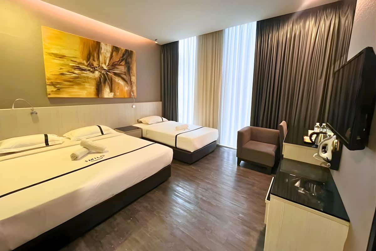 Een hotelkamer met twee bedden, een bureau, een stoel, een schilderij en een groot raam met gordijnen.