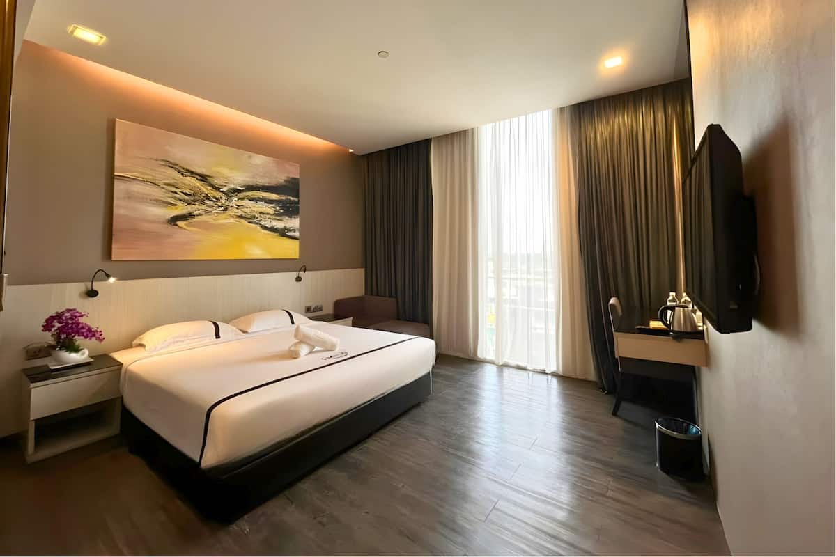 Een moderne hotelkamer met een groot bed, een schilderij, een bureau met een lamp, een televisie en een raam met gordijnen.