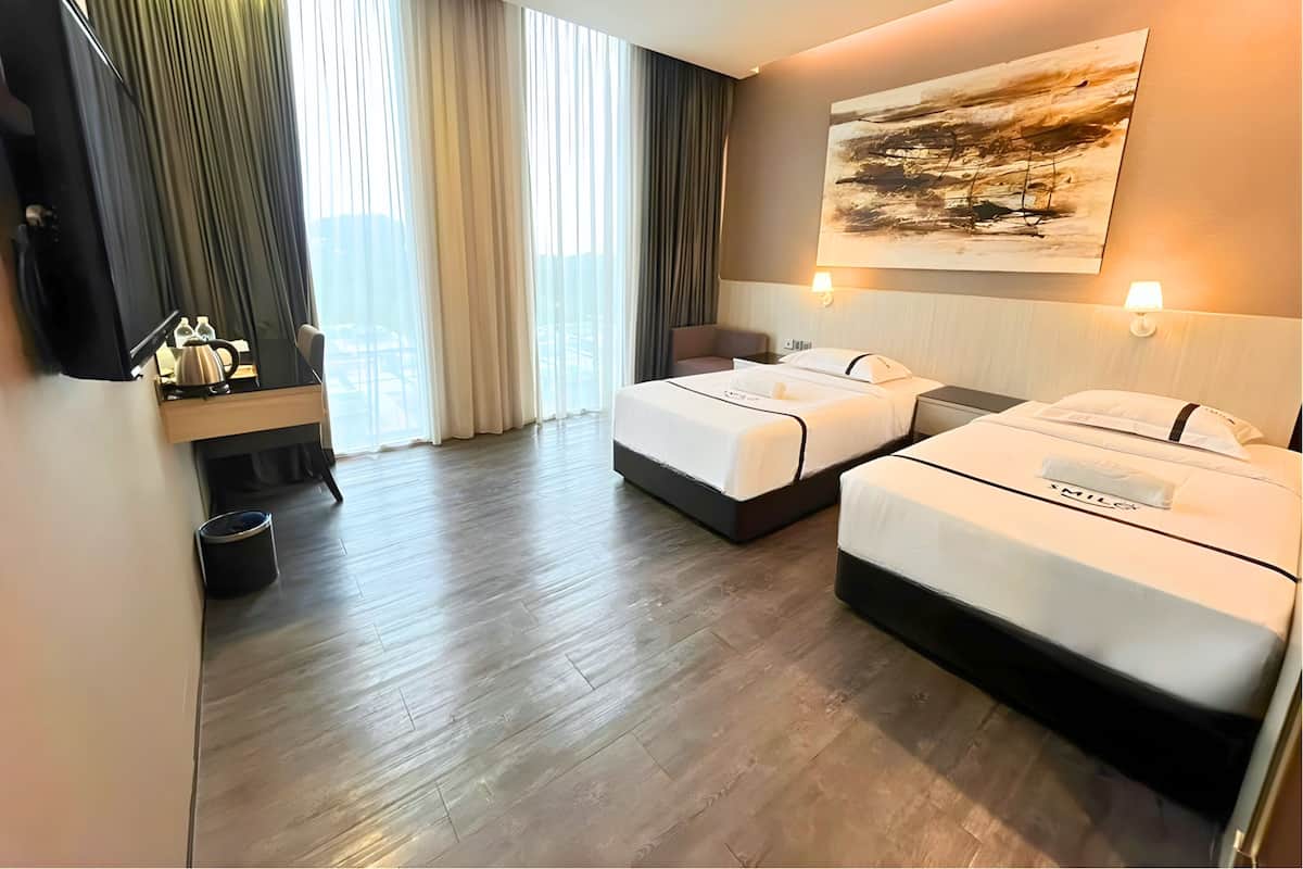 Een hotelkamer met twee bedden, een bureau, een stoel, een televisie en een groot raam met gordijnen.