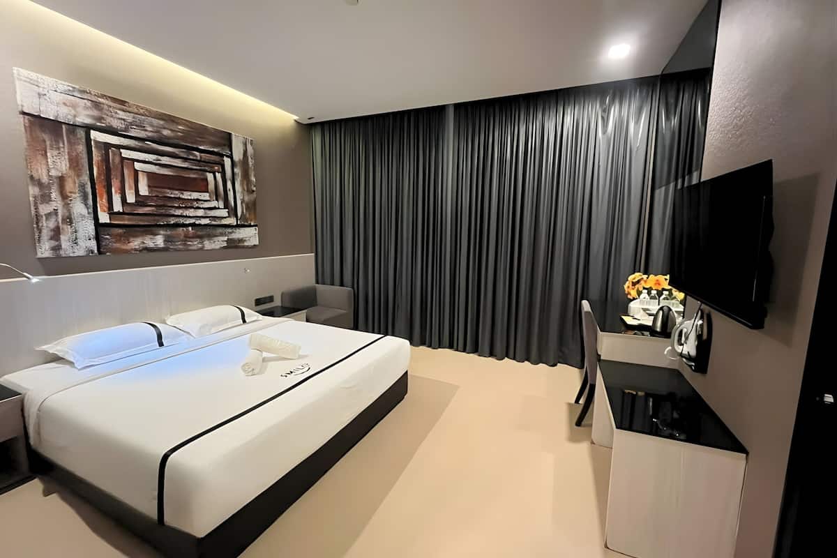 Een moderne hotelkamer met een groot bed, een bureau, een flatscreen-tv en een decoratief muurkunstwerk.