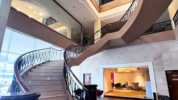Ein mehrgeschossiges Interieur mit einer geschwungenen Treppe, Glastrennvorrichtungen und einer Lobby mit Sitzgelegenheiten.
