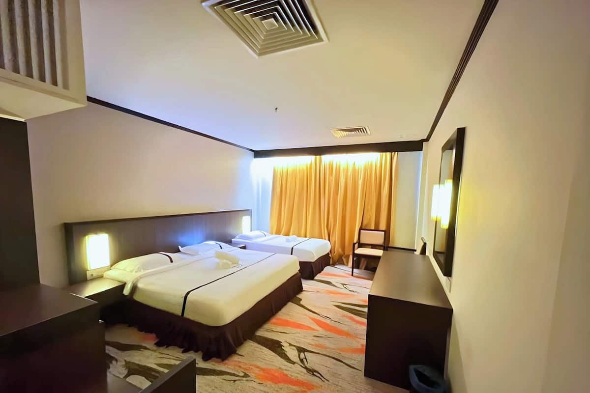 Ein Hotelzimmer mit zwei Betten, einem Schreibtisch, einem Stuhl, einer Schreibtischlampe und einem fenster mit Vorhängen.