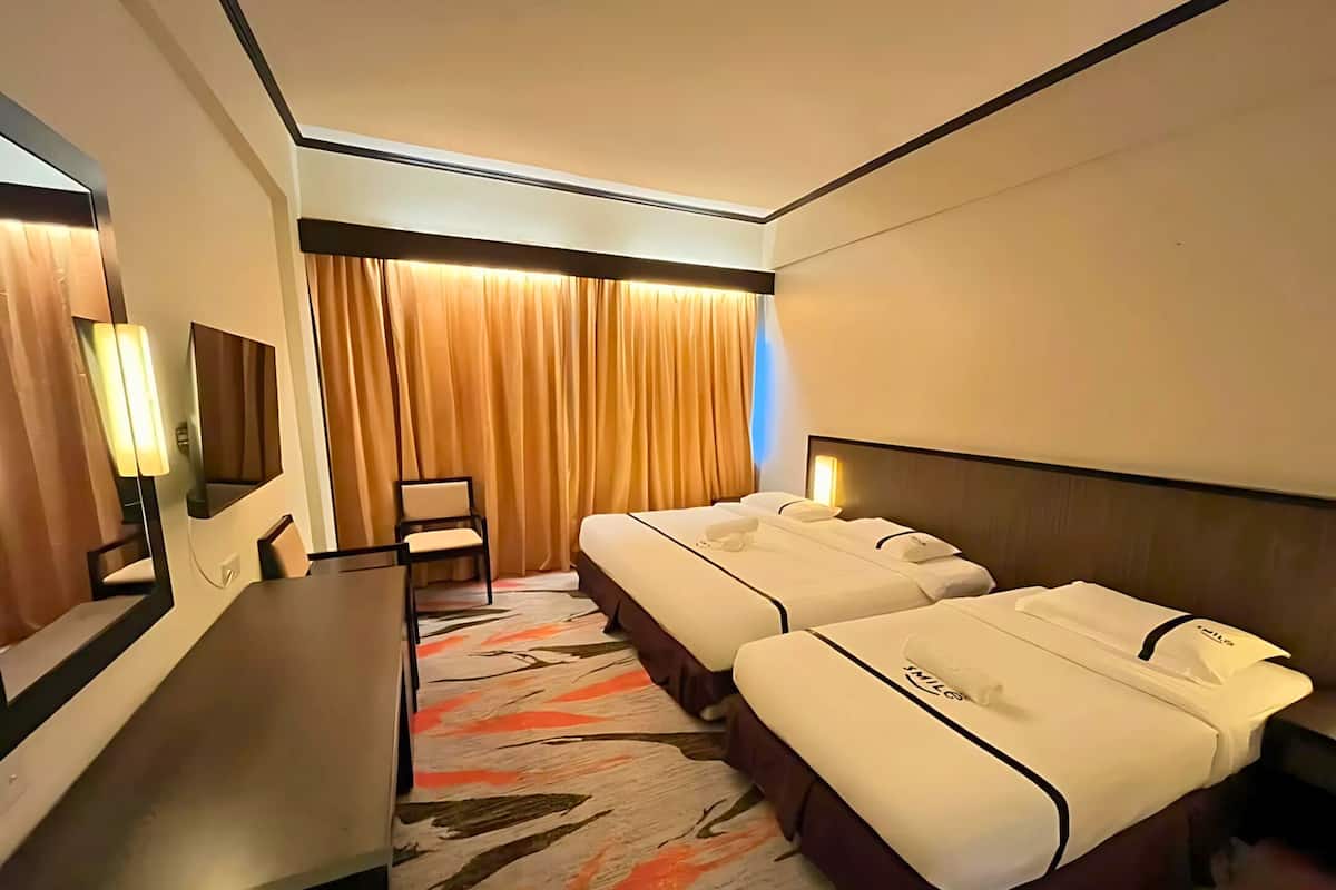 Ein Hotelzimmer mit zwei Betten, einem Schreibtisch, einem Stuhl und einem großen Spiegel.