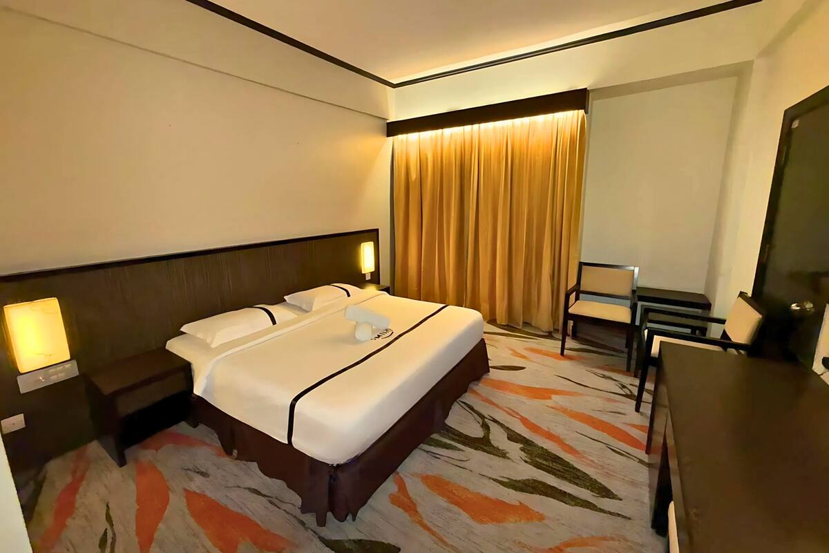 Ein Hotelzimmer mit einem großen Bett, Nachttischen, einem Schreibtisch und einem Sessel.