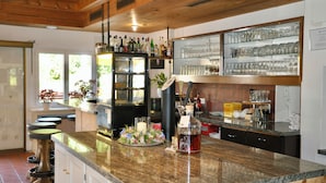 A kitchen with a granite countertop, a refrigerator, and a bar area with shelves of glassware. - Chalamandrin Hotel und Restaurant (Scuol)