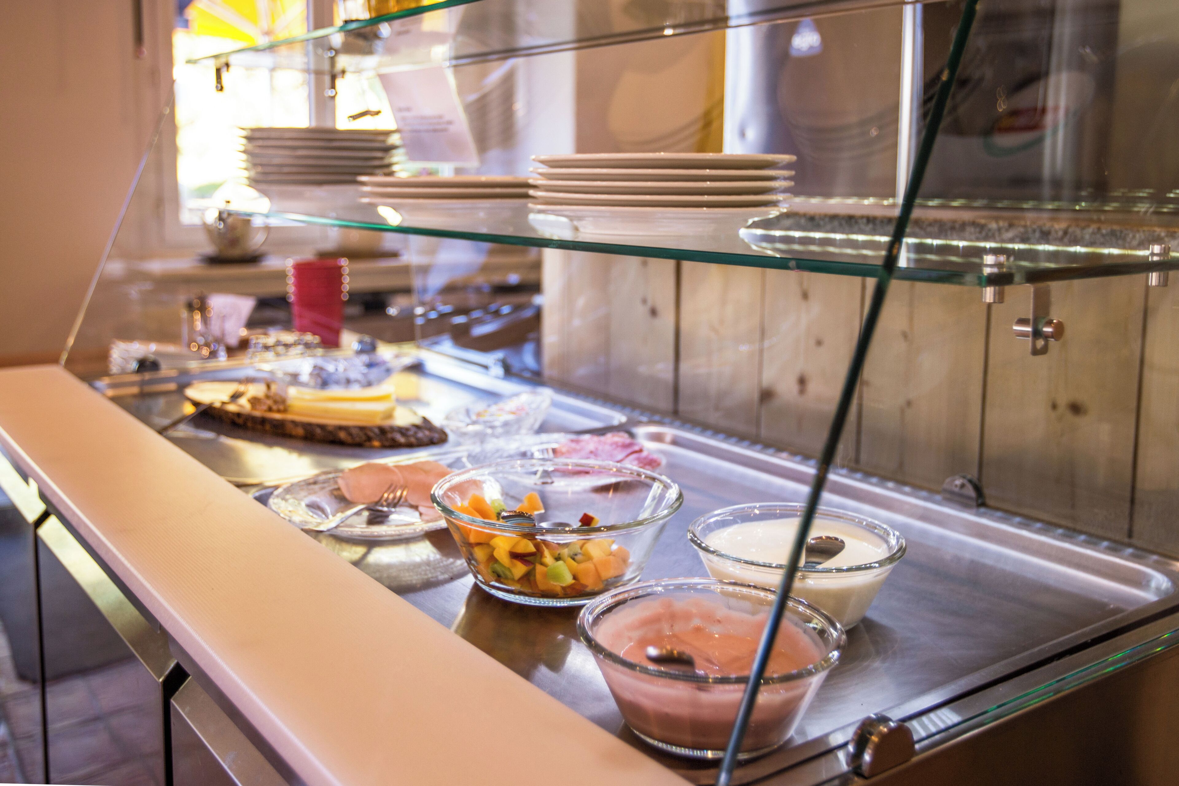 A buffet with various food items and dishes displayed on a glass counter.