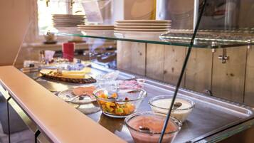 A buffet with various food items and dishes displayed on a glass counter.
