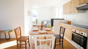 A modern kitchen with wooden cabinets, a dining table with chairs, and a visible oven. - LES LOGIS DU GENERAL - 1st floor apartment (Beaupréau-en-Mauges)