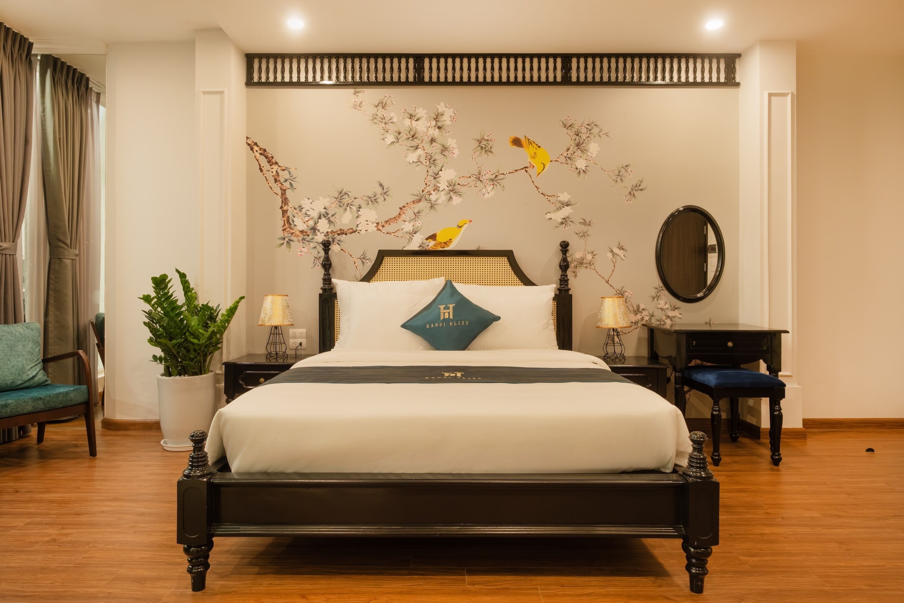 A hotel room with a bed, a potted plant, a desk, and a chair.