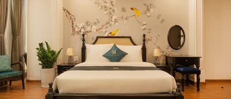 A hotel room with a bed, a potted plant, a desk, and a chair.