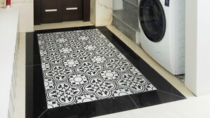 Een wasserette met een wasmachine en droger, een vloer met een patroon en een dubbele deur.