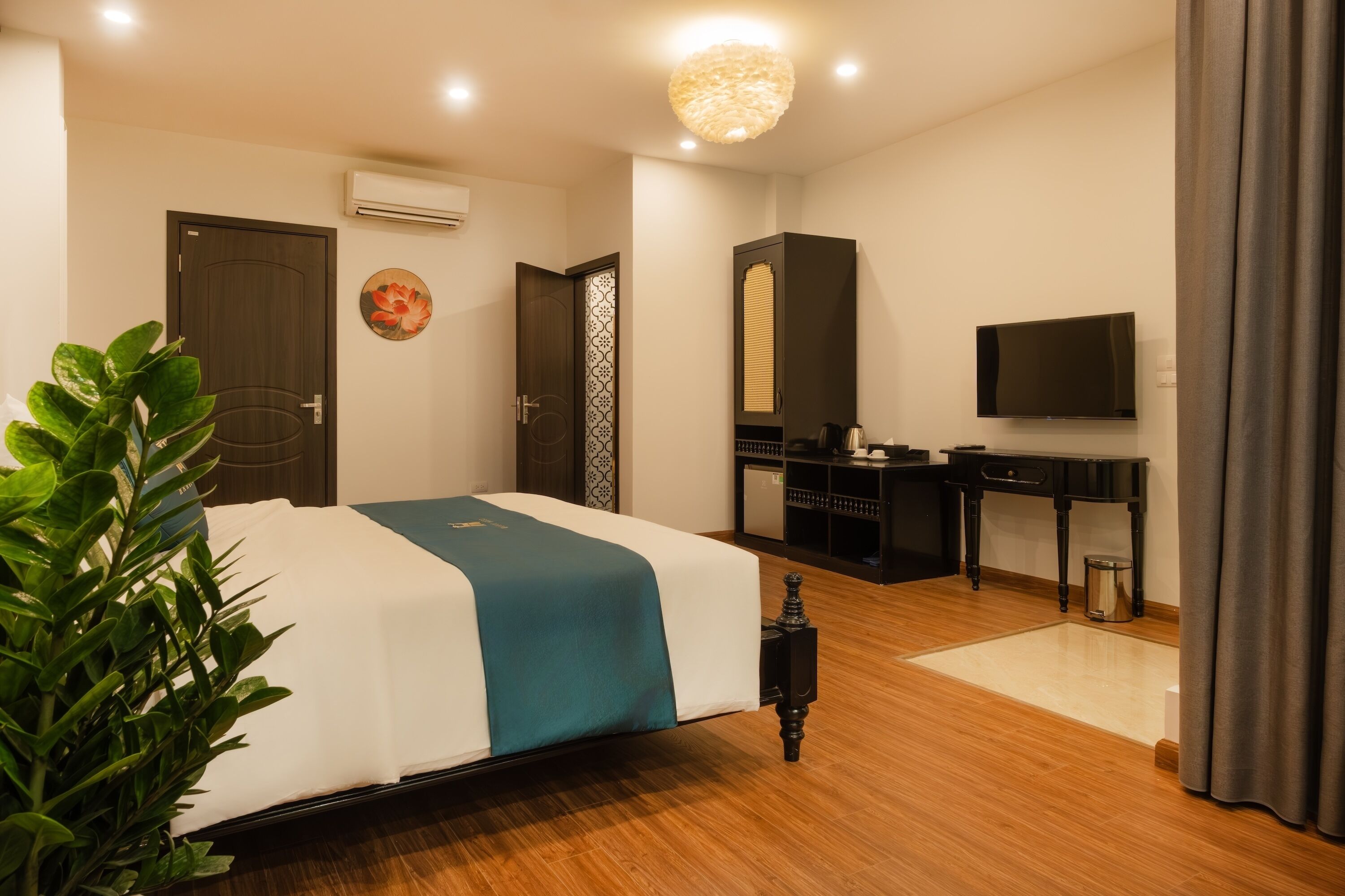 Une chambre d’hôtel avec un lit, un bureau, une télévision et une plante en pot.