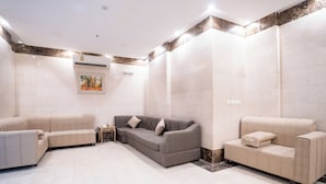 A spacious room with three beige sofas arranged in a U-shape, a small side table, and a wall-mounted air conditioning unit. - Saif Plus 3 (Makkah)