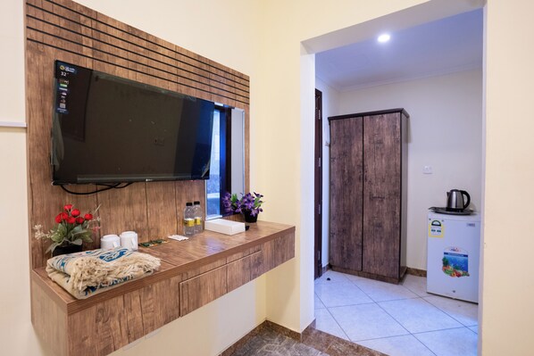 A modern bathroom with a wooden vanity, a mounted television, and a refrigerator. - Saif Plus 3 (Makkah)
