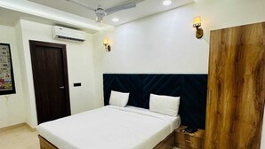 Een moderne slaapkamer met een groot bed, een plafondventilator, een airconditioning en een houten garderobe.