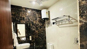 Een badkamer met een wit toilet, een wastafel, een spiegel, een plafondventilator, een douche en een handdoekhouder.