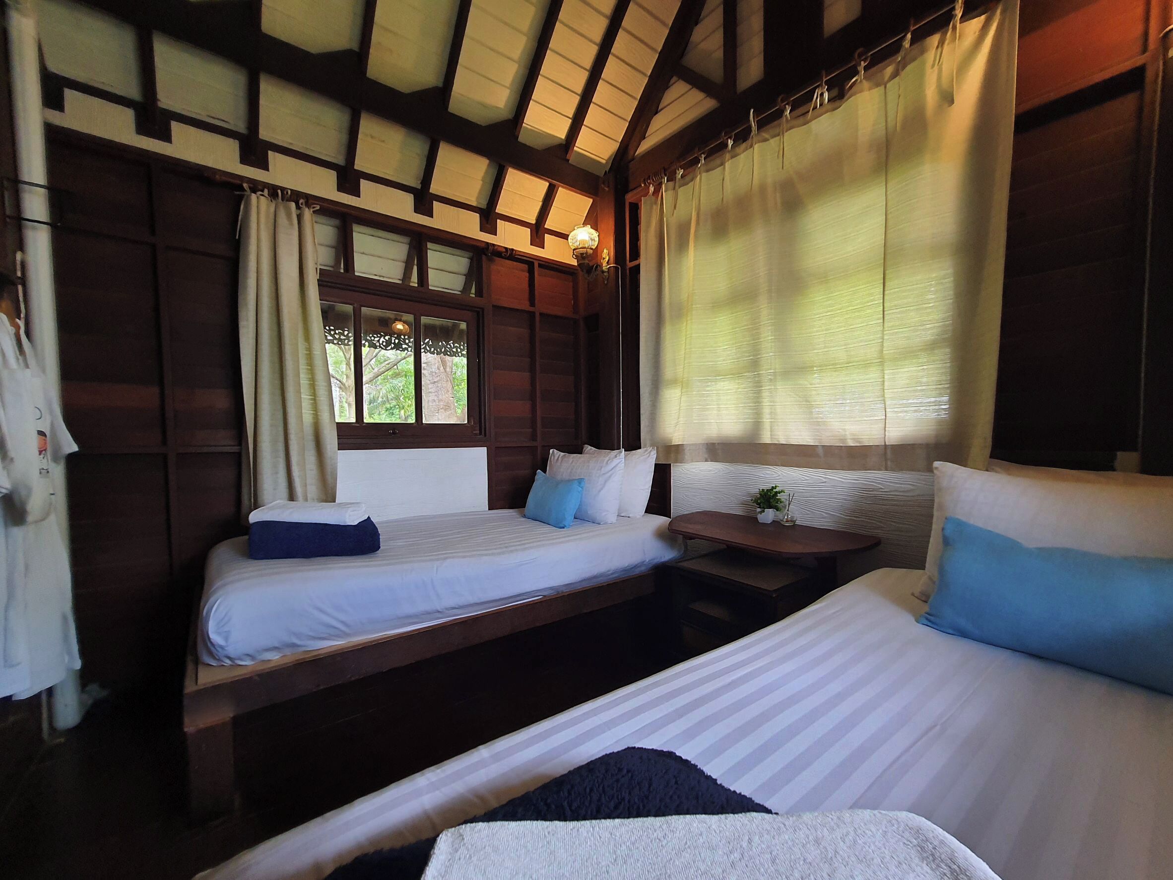 A room with two beds, a small table, and a window with curtains.
